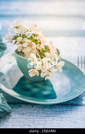 Cadre avec branche de cerisier en fleur de style bleu maritime. Ustensiles de cuisine et réglage de la table Banque D'Images