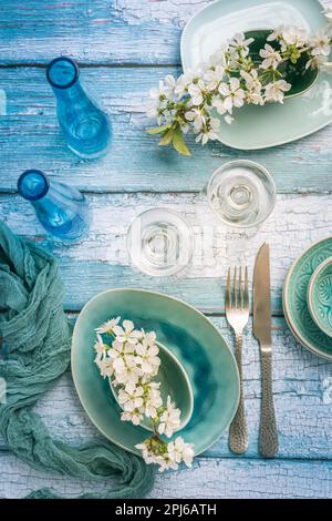 Cadre avec branche de cerisier en fleur de style bleu maritime. Ustensiles de cuisine et réglage de la table Banque D'Images