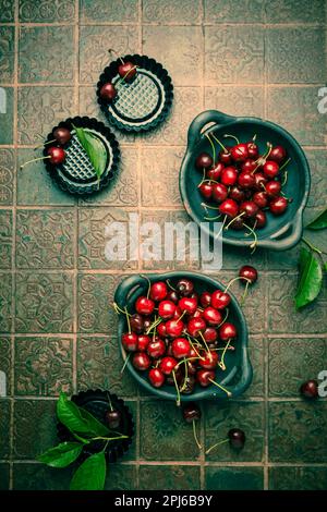 Cerises biologiques dans un bol avec une plaque de cuisson sur une table de cuisine Banque D'Images