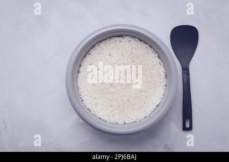 Riz dans un cuiseur à riz ou un cuiseur vapeur avec cuillère, vue du dessus Banque D'Images