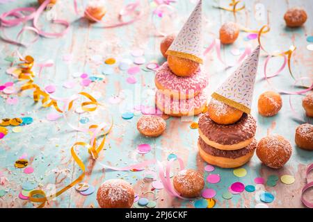 Krapfen, Berliner et beignets avec des banderoles et des confettis. Image de carnaval, d'anniversaire et de fasching colorée Banque D'Images