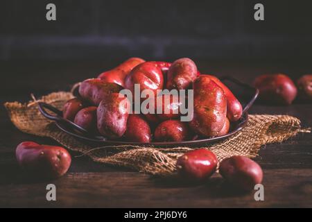 Pommes de terre rouges brutes biologiques sur fond de bois Banque D'Images