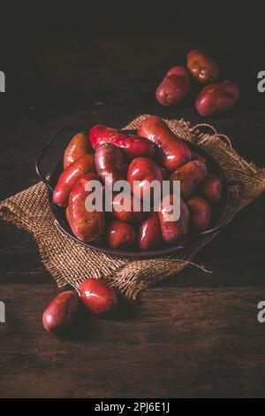 Pommes de terre rouges brutes biologiques sur fond de bois Banque D'Images