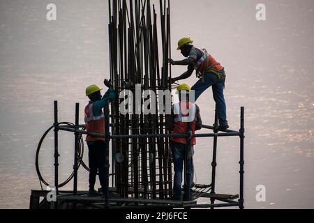 Guwahati, Inde. 27 mars 2023. Les ouvriers de la construction se sont occupés à fabriquer un poteau en béton près de la rivière Brahmaputra à Guwahati Banque D'Images