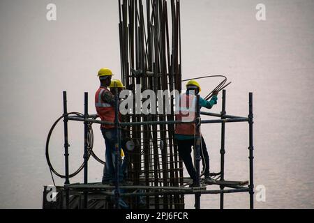 Guwahati, Inde. 27 mars 2023. Les ouvriers de la construction se sont occupés à fabriquer un poteau en béton près de la rivière Brahmaputra à Guwahati Banque D'Images