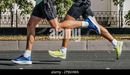 jambes deux coureurs mâles course de marathon de ville, athlètes jogging sur la route asphaltée, jeux de sports d'été Banque D'Images