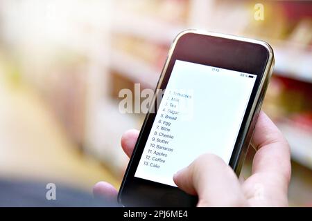 Liste d'achats sur l'écran du smartphone dans la main des femmes clients Banque D'Images