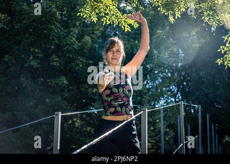 Femme pratiquant le tai chi avec une épée sur un pont. Elle fait preuve d'une grande compétence et de concentration dans sa pratique, ce qui inspire le respect et l'admirati Banque D'Images