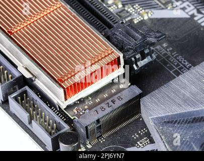 Gros plan disques SSD avec dissipateur thermique en cuivre pour ordinateur - ssd sata, NVME PCIe, SATA SSD m key, b key installé sur la carte mère de l'ordinateur moderne. Banque D'Images