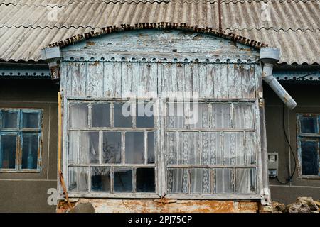 Vue à l'extérieur de petites fenêtres d'une véranda en bois d'une ancienne maison de village roumaine. Banque D'Images