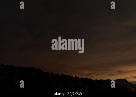 Tour de radio avec lumière rouge sur une montagne la nuit sous les nuages avec le reflet du coucher du soleil en Altai en Sibérie Banque D'Images