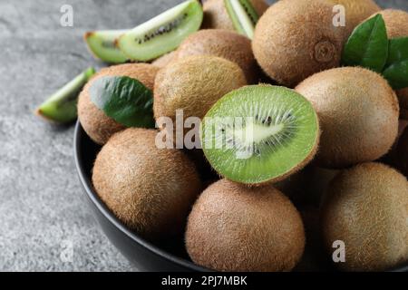 Kiwis frais mûrs dans un bol sur une table grise, en gros plan Banque D'Images