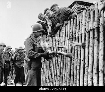 ÉTATS-UNIS Le caporal Larry Mattisk met des cigarettes dans les mains étendues de prisonniers nouvellement libérés derrière un stock dans le camp de concentration d'Allach, près de Dachau Allemagne sur 30 avril 1945. Banque D'Images