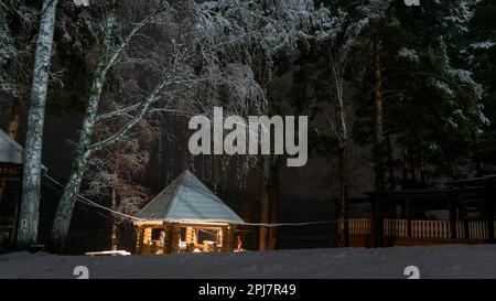 Maison de vacances avec deux femmes se reposant dans la neige sous les oiseaux la nuit avec un feu de barbecue dans l'Altai en Sibérie. Banque D'Images