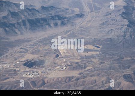 De dessus, la mine à ciel ouvert du désert ressemble à un vaste amphithéâtre sablonneux, avec des équipements et des camions massifs, éclipsés par les imposants murs de la terre. Banque D'Images