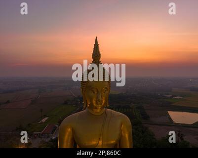 Coucher de soleil sur le paysage derrière le grand Bouddha doré de la Thaïlande à wat Muang Ang Thong Thaïlande. La plus grande statue de Bouddha au monde entourée Banque D'Images