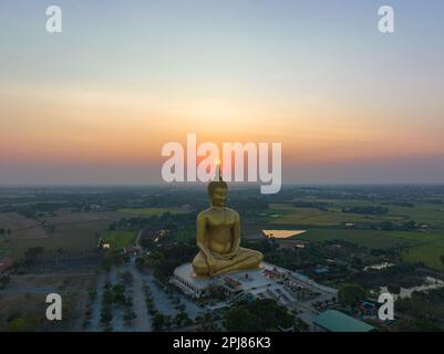 Coucher de soleil sur le paysage derrière le grand Bouddha doré de la Thaïlande à wat Muang Ang Thong Thaïlande. La plus grande statue de Bouddha au monde entourée Banque D'Images