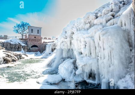 Chutes d'eau du parc Sioux Falls avec glace et neige. Cascade d'eau de fonte de neige qui coule sur le dessus dans une piscine d'eau stagnante. Banque D'Images