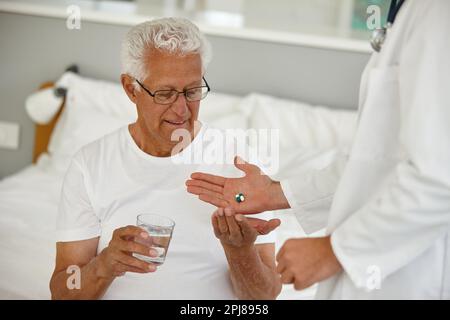 Vous vous sentirez mieux en un rien de temps. un médecin donnant à son patient âgé une dose de médicaments dans un établissement de vie assisté. Banque D'Images