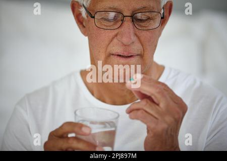 Il prend son médicament la première chose le matin. un homme âgé prenant ses médicaments. Banque D'Images