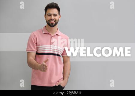 Un jeune homme heureux qui offre une poignée de main sur un arrière-plan clair. Bienvenue dans l'équipe Banque D'Images