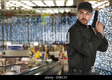 Un agent de sécurité masculin porte un uniforme avec une arme à feu dans le centre commercial Banque D'Images