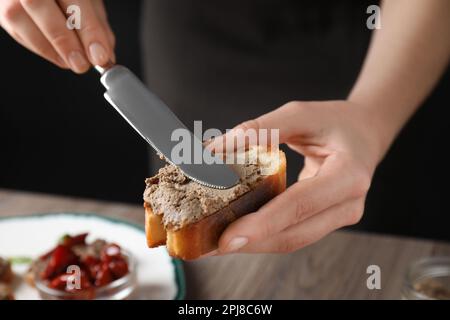 Femme qui répandait un délicieux pâté sur du pain sur une table, en gros plan Banque D'Images