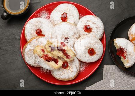 Délicieux beignets en gelée servis avec du café sur table noire, plat Banque D'Images