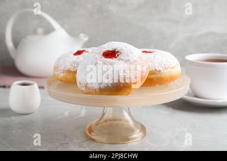 Présentoir à pâtisseries avec délicieux beignets en gelée sur table grise Banque D'Images