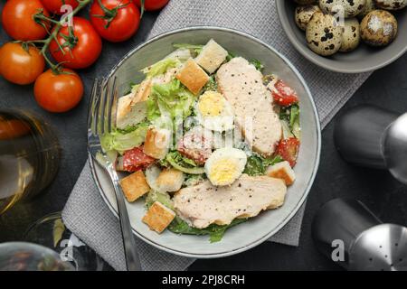 Salade César délicieuse dans un bol sur une table noire, à plat Banque D'Images