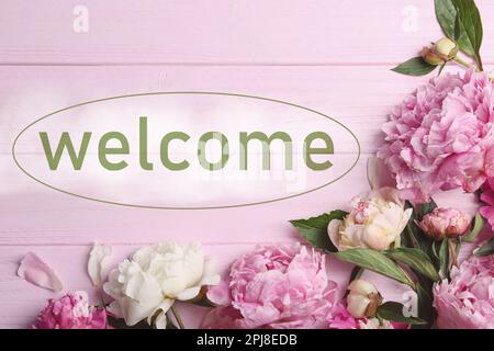 Belles pivoines et mot DE BIENVENUE sur table en bois rose, plat Banque D'Images