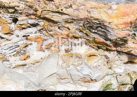 Formation de roche d'une falaise près de la mer dans les couleurs jaune, orange, blanc et vert. Banque D'Images