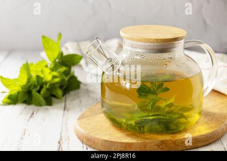 Bio aromathérapie détente médical boisson saine. Théière de tisane naturelle fraîche avec feuilles de menthe fraîche sur une table en bois rustique. Banque D'Images