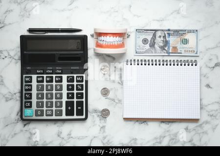 Composition de pose plate avec modèle de typographie dentaire pédagogique et argent sur table en marbre blanc. Traitement coûteux Banque D'Images