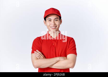 Un homme de livraison asiatique souriant et amical présente des bras croisés bleus uniformes Banque D'Images