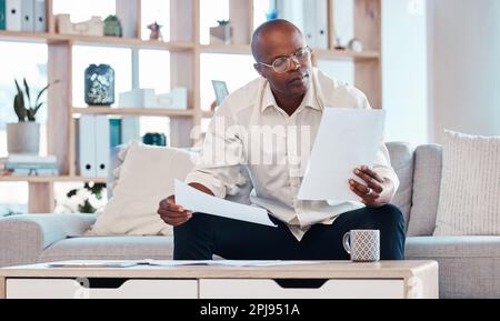 Homme lisant des documents dans la maison de salon pour la planification, le rapport budgétaire et le contrat d'investissement. Homme noir, notes et travail à distance dans le salon de l'impôt Banque D'Images