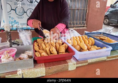 Une vue latérale d'une femme non identifiée qui vend de la nourriture de rue indonésienne. un type de takjil qui est frite à la perfection. Ramadan 2023 Banque D'Images