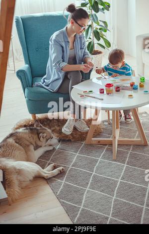 Maman et enfant peignent ensemble à la maison avec le chien Banque D'Images