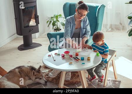 Maman et enfant peignent ensemble à la maison avec le chien Banque D'Images