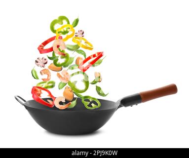 Différents ingrédients savoureux tombant dans le wok sur fond blanc Banque D'Images