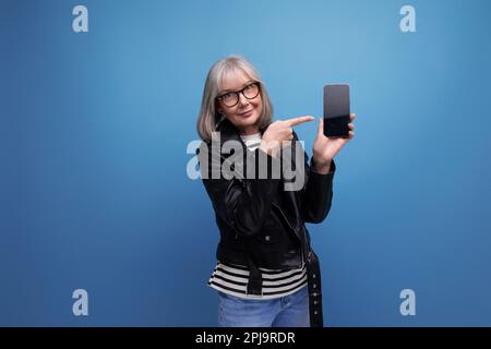 elégant moderne 60s moderne vieille dame granny avec cheveux gris tenant téléphone avec mocap sur fond clair avec espace de copie Banque D'Images