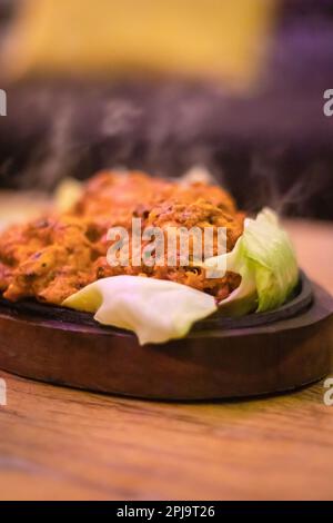 poulet au beurre chaud en plaat de bois à partir d'un angle plat Banque D'Images