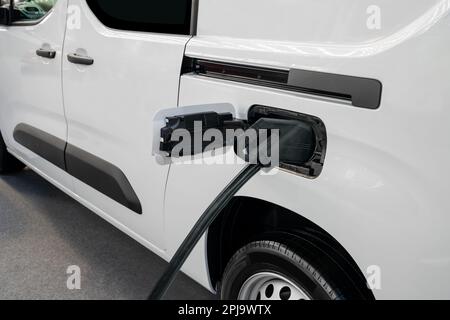 Camionnette électrique avec câble de charge connecté. Photo de haute qualité Banque D'Images