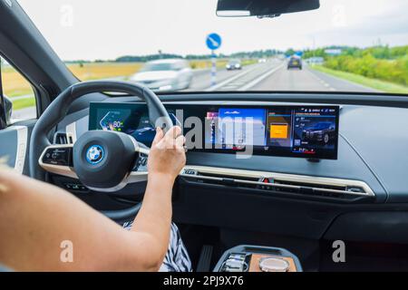 Belle vue chère de l'intérieur de la BMW iX40 voiture électrique conduite par une femme conducteur sur l'autoroute. Suède. Banque D'Images