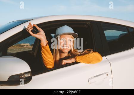 Une femme voyageant dans une voiture montrant les clés ouvertes. Voyage sur route avec location automobile vacances transport assurance concept. Fille achetant auto Banque D'Images