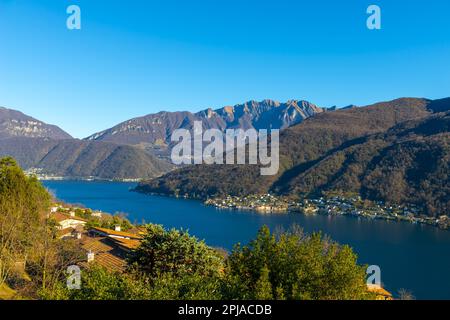 Vue panoramique sur le lac de Lugano et le village avec la montagne en une journée ensoleillée à Vico Morcote, Tessin en Suisse. Banque D'Images