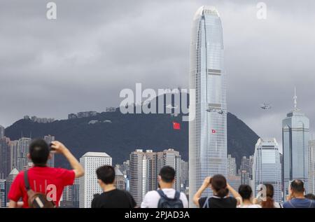 Les membres du public regardent les hélicoptères du Service de vol du Gouvernement portant les drapeaux nationaux et SAR passer devant et défilé en mer pendant la cérémonie de levée de drapeau à la place Bauhinia d'or à WAN Chai pour célébrer le 25th anniversaire de la création de la HKSAR, en regardant depuis la promenade Tsim Sha Tsui, pendant que la police patrouille et garde-pied. 01JUL22 SCMP / Tam. Nora Banque D'Images