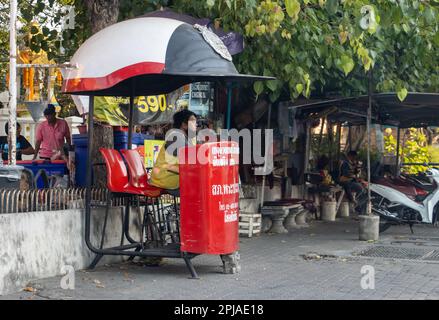 SAMUT PRAKAN, THAÏLANDE, LE 28 2023 JANVIER, Un chauffeur de taxi est assis à un poste de contrôle de la circulation sur le trottoir à côté d'une station de moto-taxi Banque D'Images