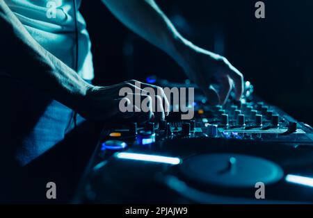 Techno Party DJ jouant de la musique avec un mélangeur audio et des platines. Club disc jockey mélangeant des morceaux de musique sur la fête en gros plan, se concentrer sur les mains Banque D'Images