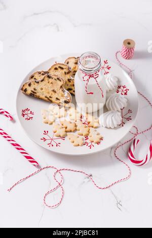 Bouteille de lait avec un stollen de Noël traditionnel, petits biscuits et canne à sucre sur fond blanc. Pain de Noël allemand Banque D'Images